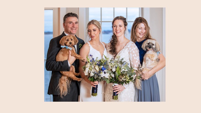 Smiling wedding party with brides, mom and dad, and two Havanese