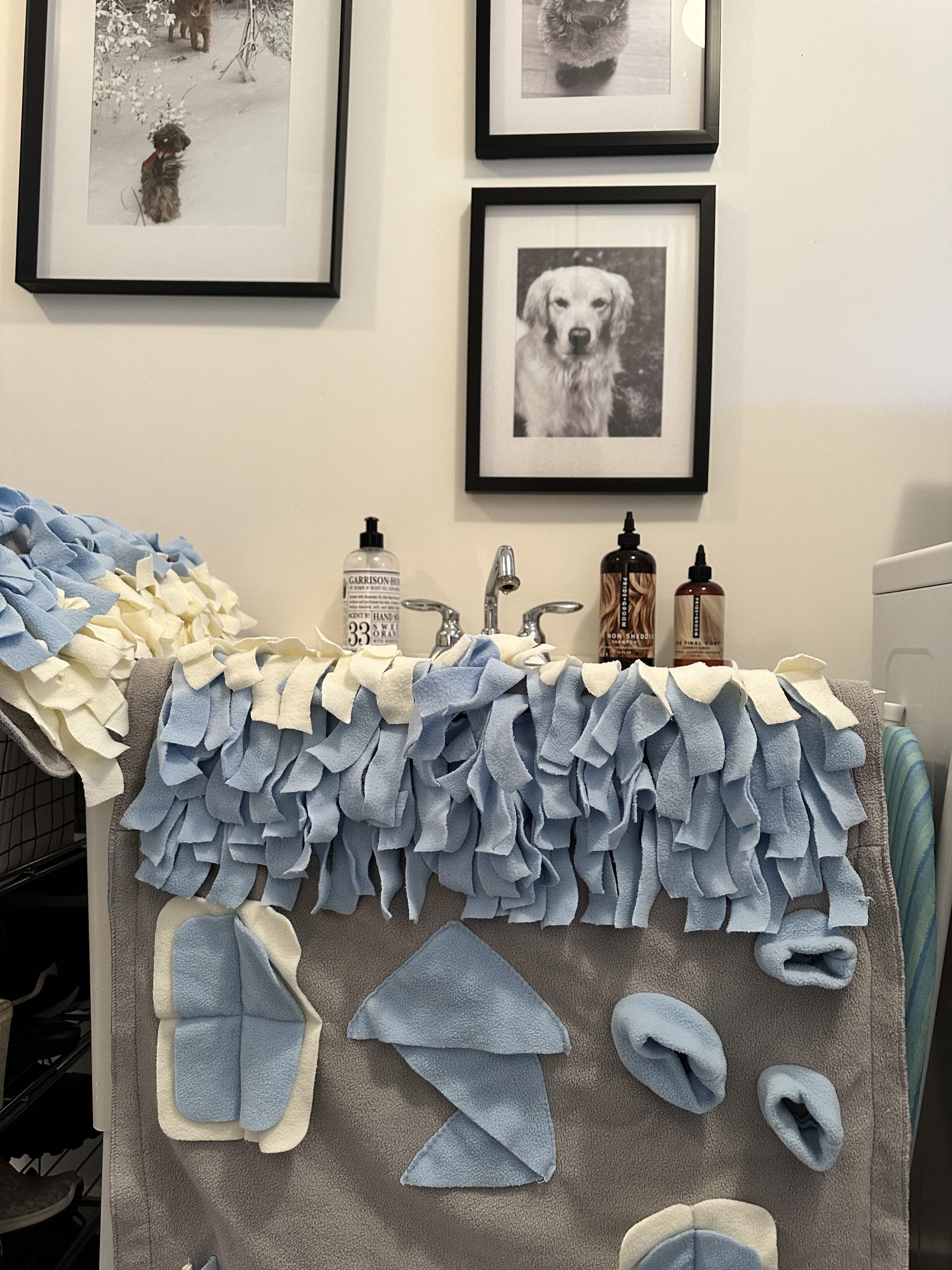 Fleece snuffle mat air drying in laundry room with pics of dogs above sink