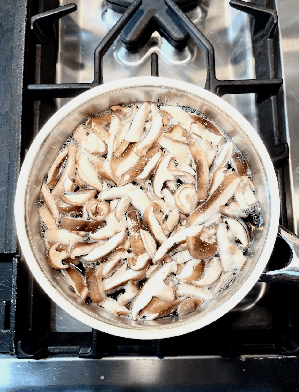 Pan of sliced mushrooms in water on stovetop