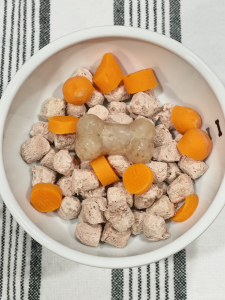 Frozen Mushroom Broth for Dogs Bone atop Dehydrated Raw Food and Cooked Carrots