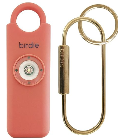 Product photo of salmon colored personal alarm with brass hardware
